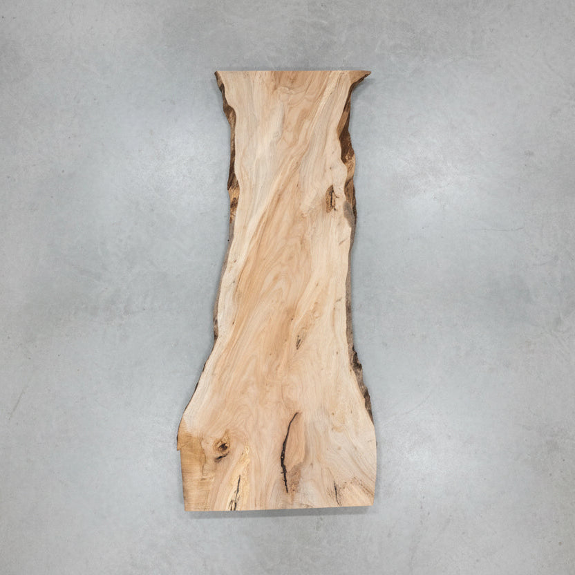 Large wooden slab in a workshop setting with tools and equipment around