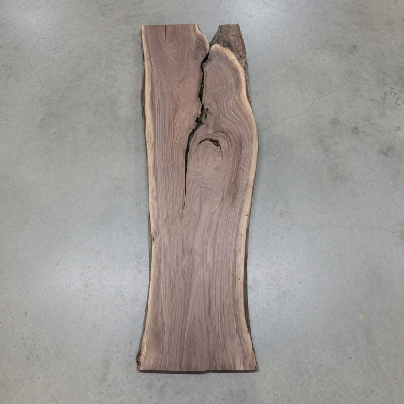 Stack of wooden slabs with visible grain patterns against a textured wall.