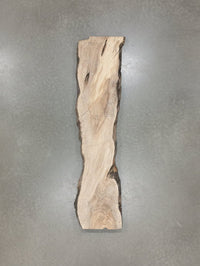 Wooden slabs stacked against a wall in a workshop setting. view 1